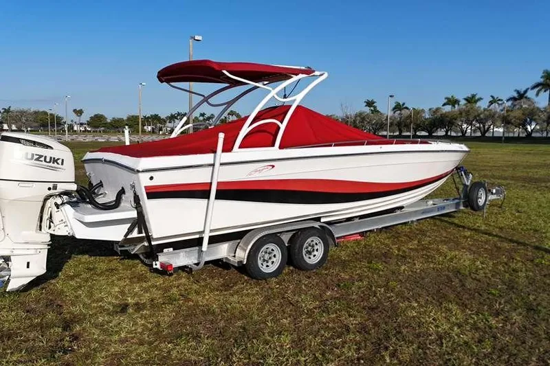Slide: The Image of 1992 Baja 280 Sportfish boat with red canopy on trailer, parked on grass. - 2