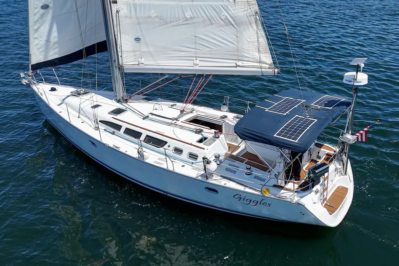 The Image of 2002 Jeanneau Sun Odyssey 43 sailboat on water with solar panels and sails up. - 1