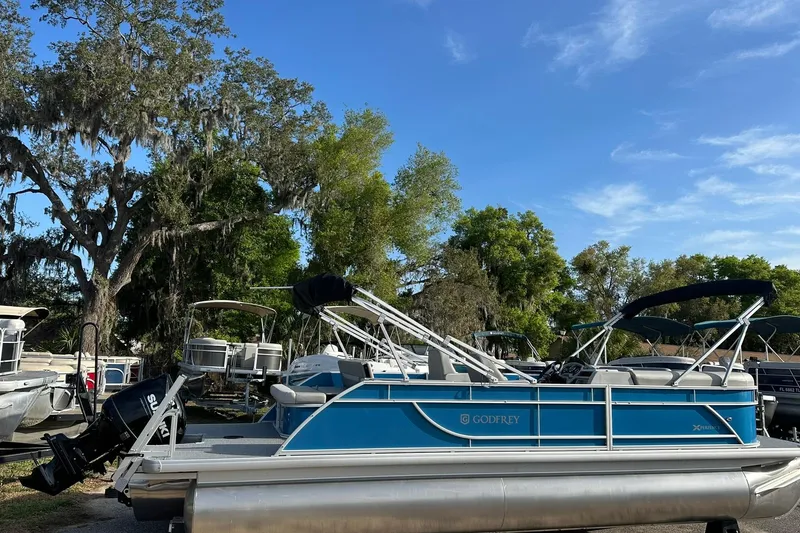 The Image of 2026 Sweetwater EX 2286 SFLX pontoon boat with blue accents, parked outdoors. - 0