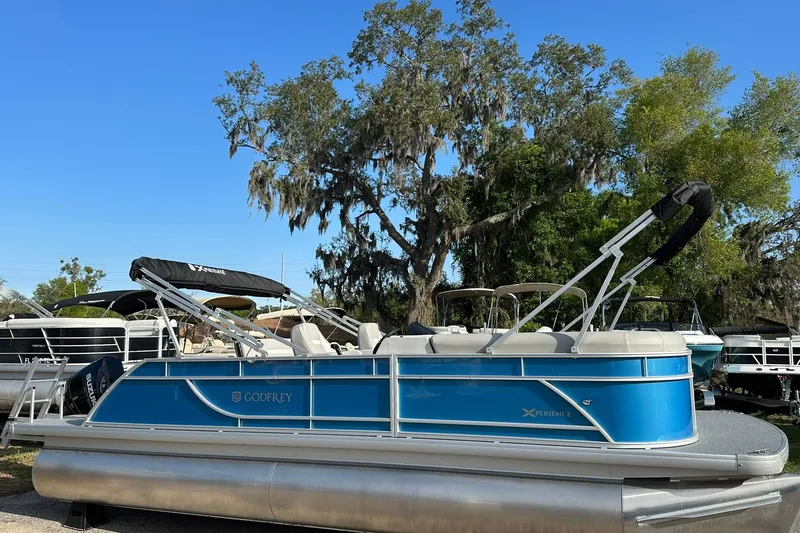 Slide: The Image of 2026 Sweetwater EX 2286 SFLX pontoon boat, blue exterior, parked outdoors under clear sky. - 1