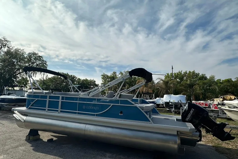 Slide: The Image of 2026 Sweetwater EX 2286 SFLX pontoon boat with Suzuki outboard motor, parked outdoors. - 27