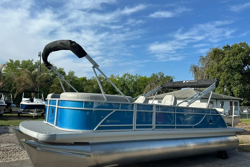 Slide: The Image of 2026 Sweetwater EX 2286 SFLX pontoon boat with blue exterior, parked outdoors. - 6