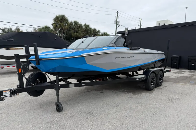 Slide: The Image of 2026 Nautique Ski Nautique boat in blue and gray on a trailer, parked outdoors. - 6