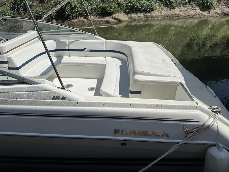 Slide: The Image of 2000 Formula 330 SS boat with white seating, docked by a riverbank. - 2