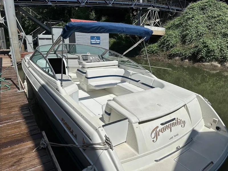 Slide: The Image of 2000 Formula 330 SS boat docked, featuring spacious seating and a blue canopy. - 37