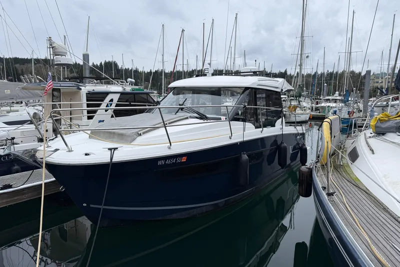 Slide: The Image of 2020 Jeanneau NC 895 boat docked in a marina with surrounding sailboats. - 1