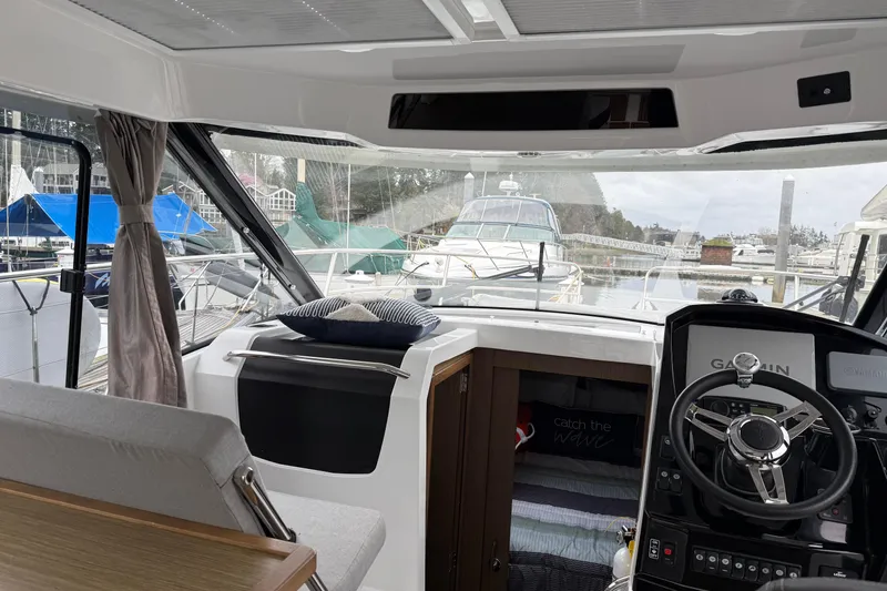 Slide: The Image of Interior view of 2020 Jeanneau NC 895 boat with steering wheel and marina backdrop. - 18