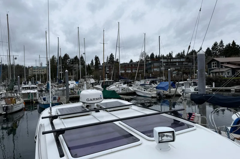 Slide: The Image of Jeanneau NC 895 boat docked in a marina, surrounded by sailboats, under cloudy skies. - 32