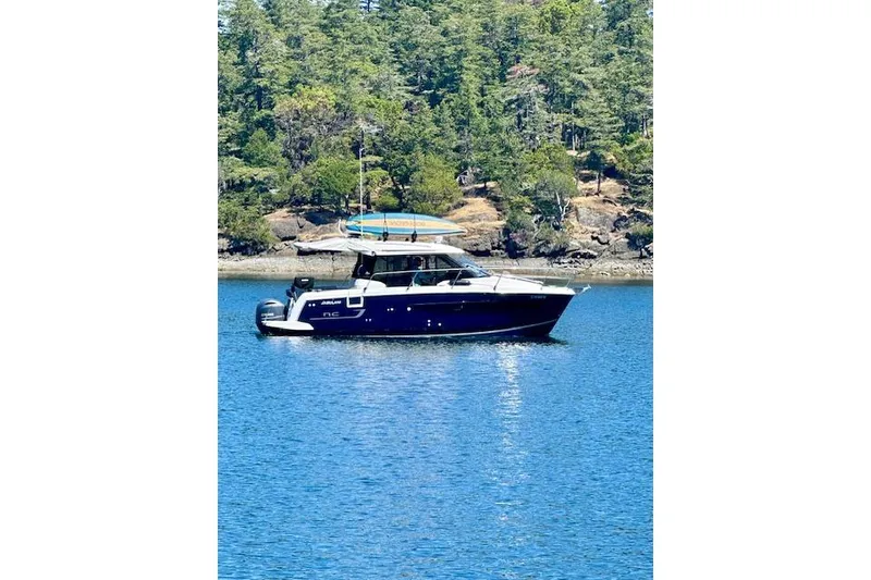 Slide: The Image of 2020 Jeanneau NC 895 boat on calm water with forested shoreline background. - 35