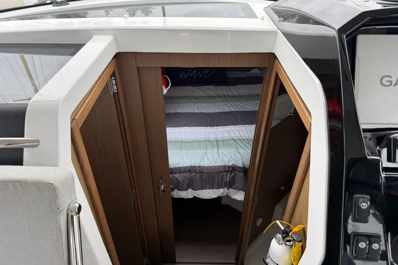 Slide: The Image of 2020 Jeanneau NC 895 cabin entrance with striped bedding and wooden doors. - 9