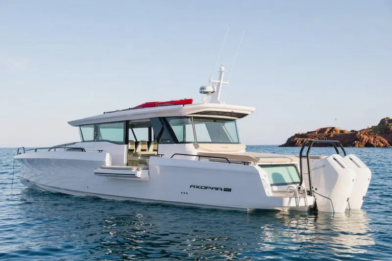 Slide: The Image of 2026 Axopar 45 XC Cross Cabin boat on calm sea near rocky coastline. - 1