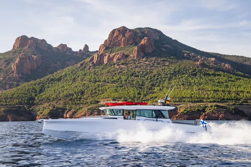 Slide: The Image of 2026 Axopar 45 XC Cross Cabin cruising near scenic rocky coastline. - 2