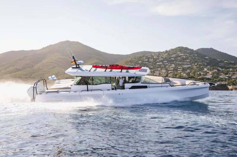Slide: The Image of 2026 Axopar 45 XC Cross Cabin cruising on water with scenic mountain backdrop. - 3