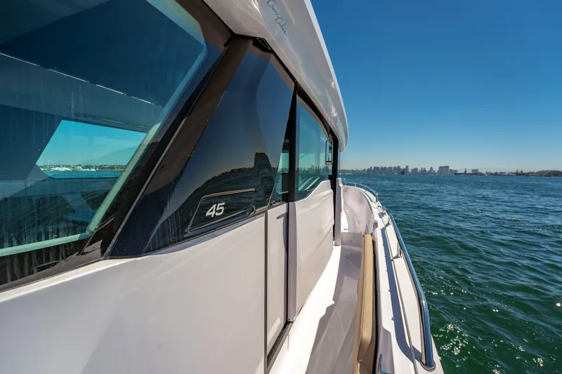 Slide: The Image of 2026 Axopar 45 XC Cross Cabin cruising on open water with city skyline in background. - 19