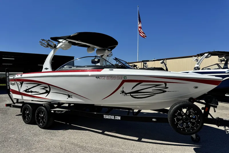 The Image of 2015 Tigé Z3 boat on trailer, white with red accents, parked outdoors. - 1