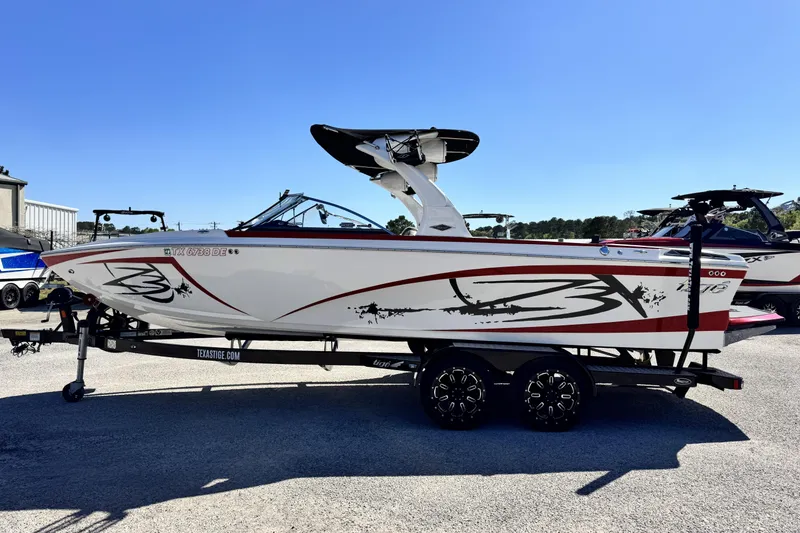Slide: The Image of 2015 Tigé Z3 boat on trailer, white with red accents, parked outdoors. - 6