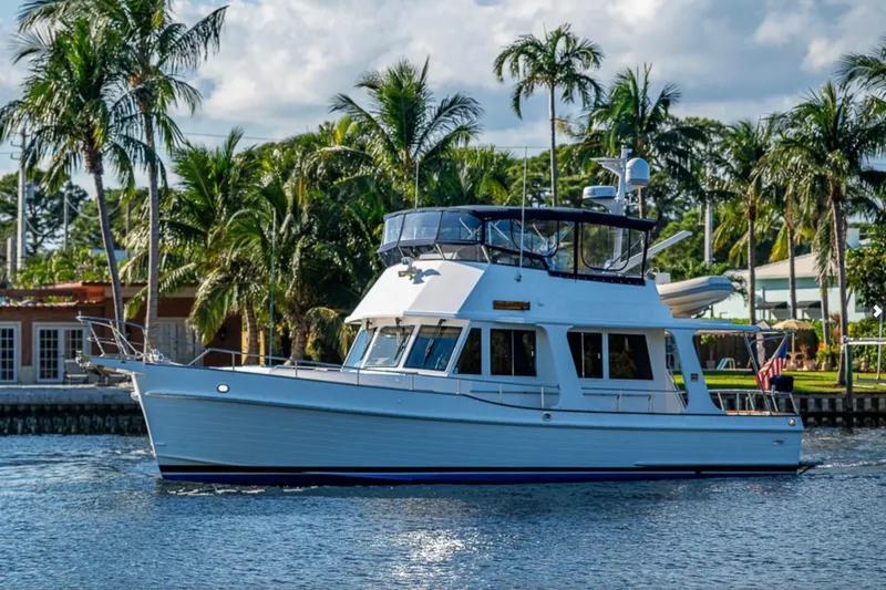 The Image of 2007 Grand Banks 47 Europa yacht cruising near palm trees and waterfront homes. - 2