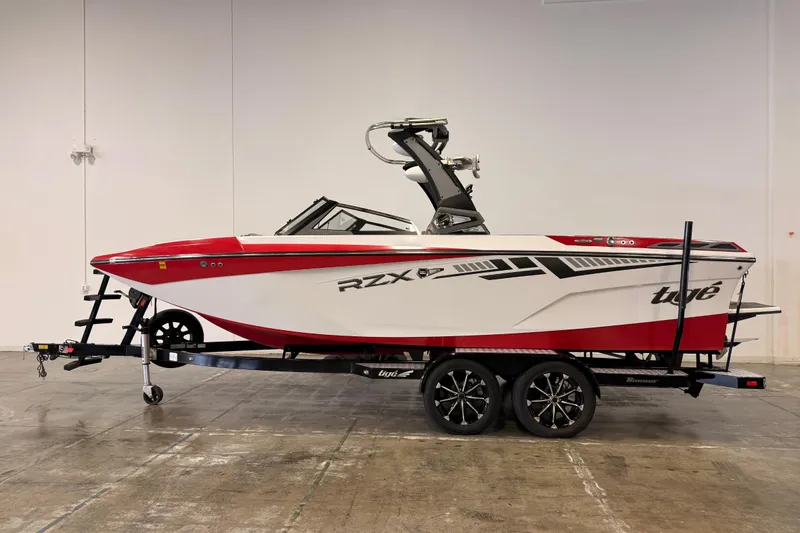 The Image of 2018 Tigé RZX2 boat on trailer, red and white design, indoor setting. - 1