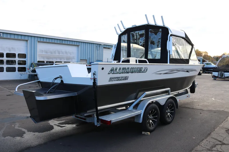 Slide: The Image of 2026 Alumaweld Intruder Outboard 22 boat on trailer, parked outside a garage. - 4