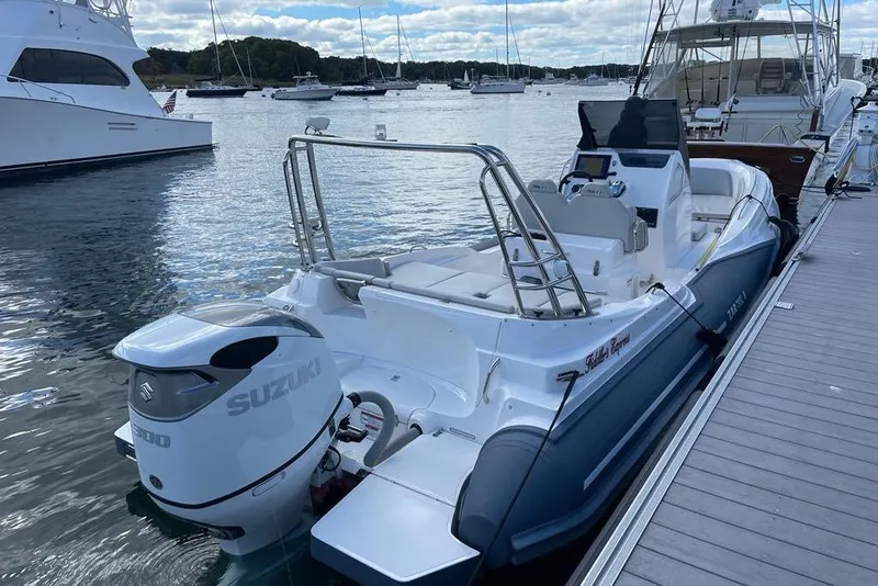 Slide: The Image of 2022 Zar 79SL boat docked, featuring Suzuki outboard motor, in a marina setting. - 2