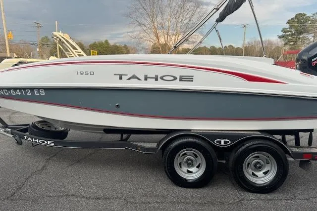 Slide: The Image of 2018 Tahoe 1950 boat on trailer, gray and white with red accents, parked outdoors. - 4