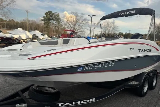 Slide: The Image of 2018 Tahoe 1950 boat on trailer, white with red accents, parked outdoors. - 3