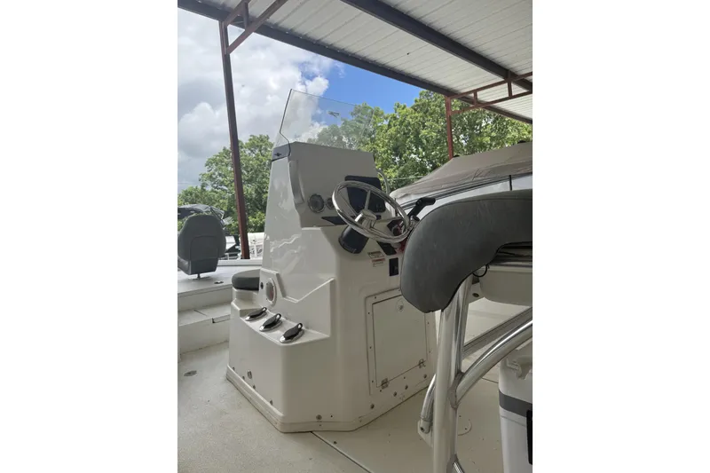 Slide: The Image of 2024 Avid 21 FST boat console with steering wheel under a covered dock. - 2