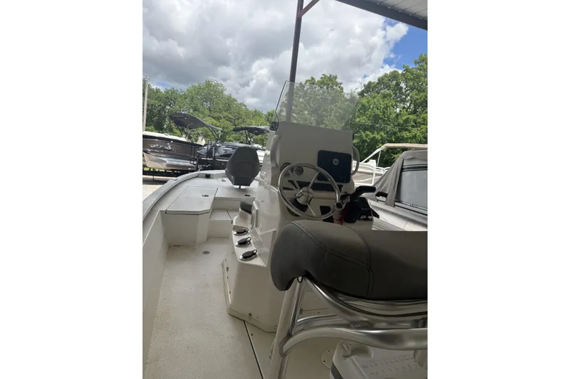 Slide: The Image of 2024 Avid 21 FST boat interior with steering wheel and seating under cloudy sky. - 9