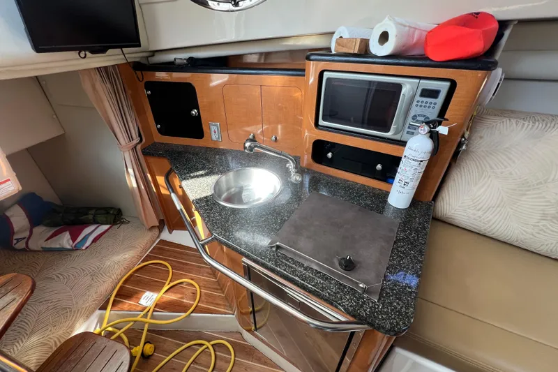 Slide: The Image of 2007 Robalo R305 Walkaround cabin with kitchenette, featuring sink, microwave, and fire extinguisher. - 14