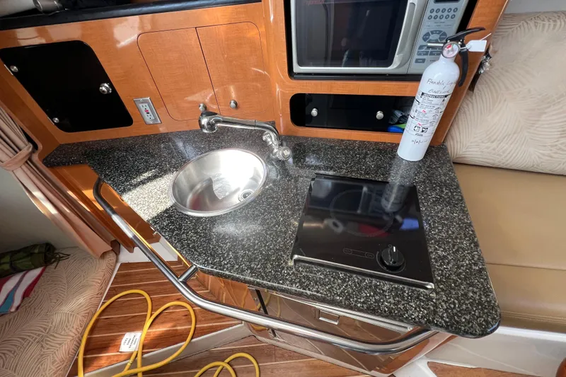 Slide: The Image of 2007 Robalo R305 Walkaround boat kitchen with sink, stove, and fire extinguisher. - 16