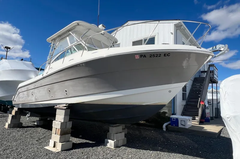 Slide: The Image of 2007 Robalo R305 Walkaround boat on blocks, parked outdoors under a clear blue sky. - 2