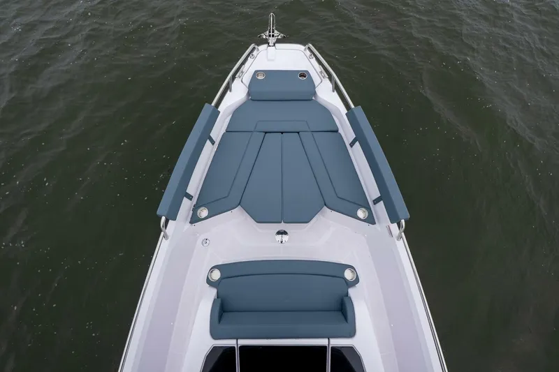 Slide: The Image of 2026 Axopar 29 XC Cross Cabin boat with blue seating on calm water. - 16