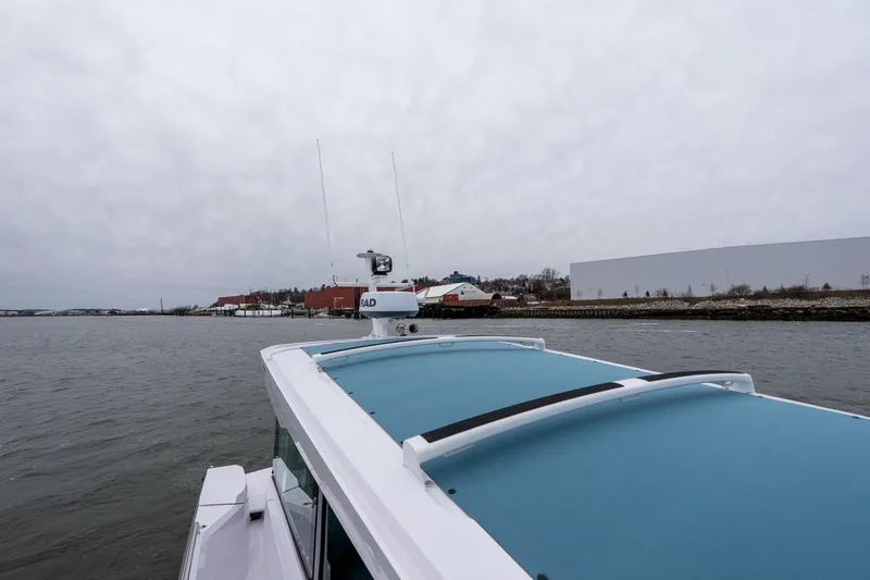 Slide: The Image of 2026 Axopar 29 XC Cross Cabin cruising near a coastal town under cloudy skies. - 19