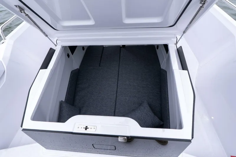 Slide: The Image of 2026 Axopar 29 XC Cross Cabin storage compartment with cushioned interior and open hatch. - 9