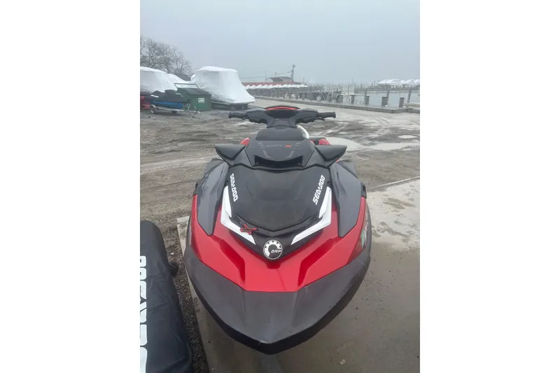 Slide: The Image of 2024 Sea-Doo RXT-X 325 jet ski in red and black, parked near a marina. - 7