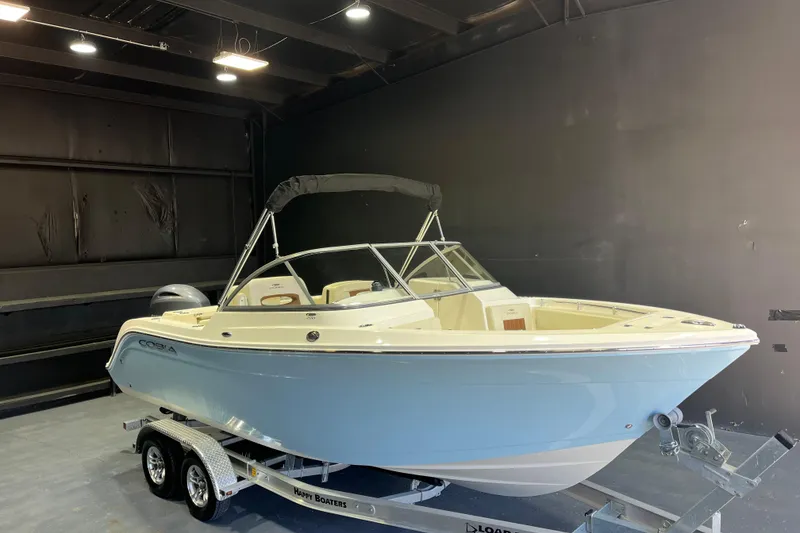 The Image of 2023 Cobia 220 Dual Console boat on trailer in indoor setting. - 1