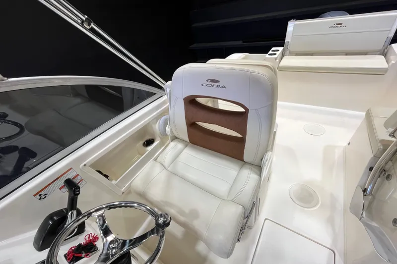 Slide: The Image of 2023 Cobia 220 Dual Console boat interior with steering wheel and seating. - 12