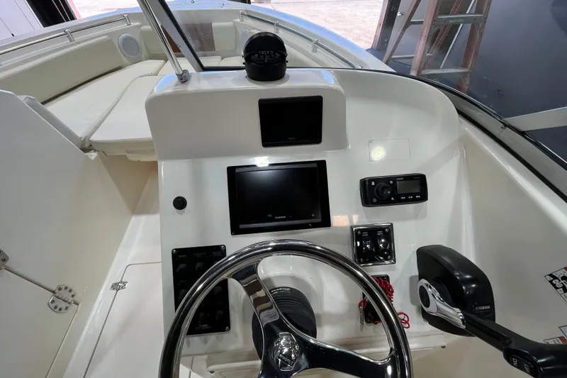 Slide: The Image of 2023 Cobia 220 Dual Console boat dashboard with steering wheel and electronic controls. - 15