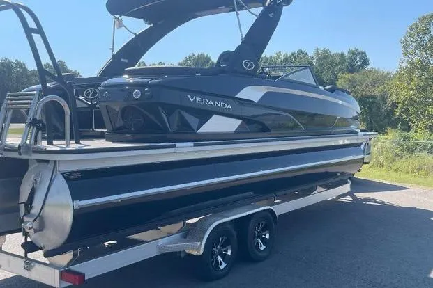 Slide: The Image of 2023 Veranda V One 25 pontoon boat on trailer, sleek black design, parked outdoors. - 13