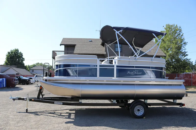 The Image of 2025 SunChaser Vista 18 LR pontoon boat on trailer, parked outdoors. - 1