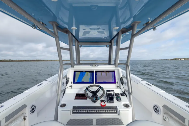 Slide: The Image of 2024 Invincible 35 Catamaran helm with dual screens, steering wheel, and ocean view. - 22