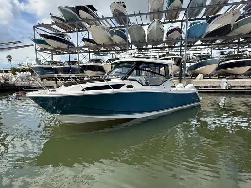 Slide: The Image of A 2027 Boston Whaler 325 Conquest is docked in the water near a boat rack. - 6