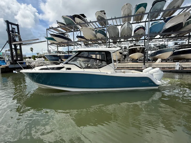 Slide: The Image of A 2027 Boston Whaler 325 Conquest is docked in the water near a boat rack. - 5