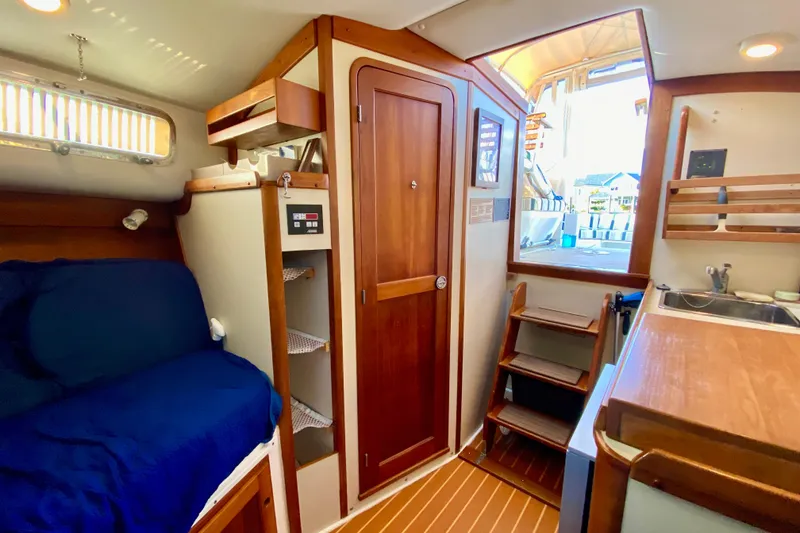 Slide: The Image of 2003 Legacy Yachts 28 interior galley with sink, wooden countertop, and storage shelves. - 12
