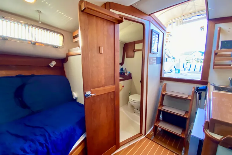 Slide: The Image of Interior of 2003 Legacy Yachts 28, featuring cozy cabin with wood accents and compact kitchen. - 13