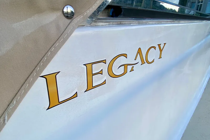 Slide: The Image of 2003 Legacy Yachts 28 with striped seating and wooden table on calm water. - 19