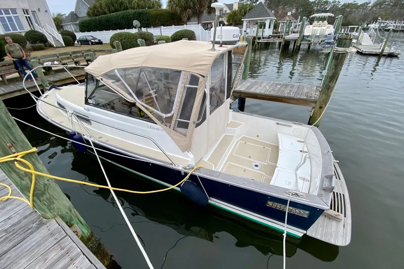 Slide: The Image of 2003 Legacy Yachts 28 docked at a marina with beige canopy. - 2