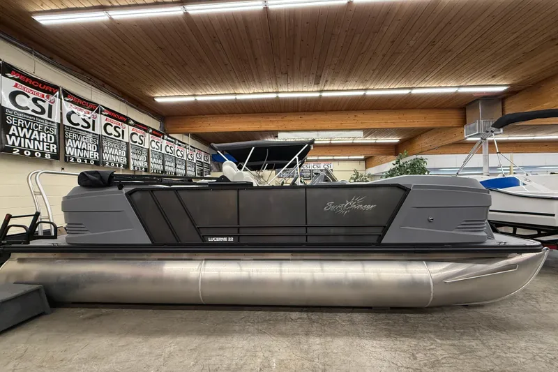 The Image of 2025 SunChaser Lucerne 22 LR DH pontoon boat displayed indoors with award banners. - 1