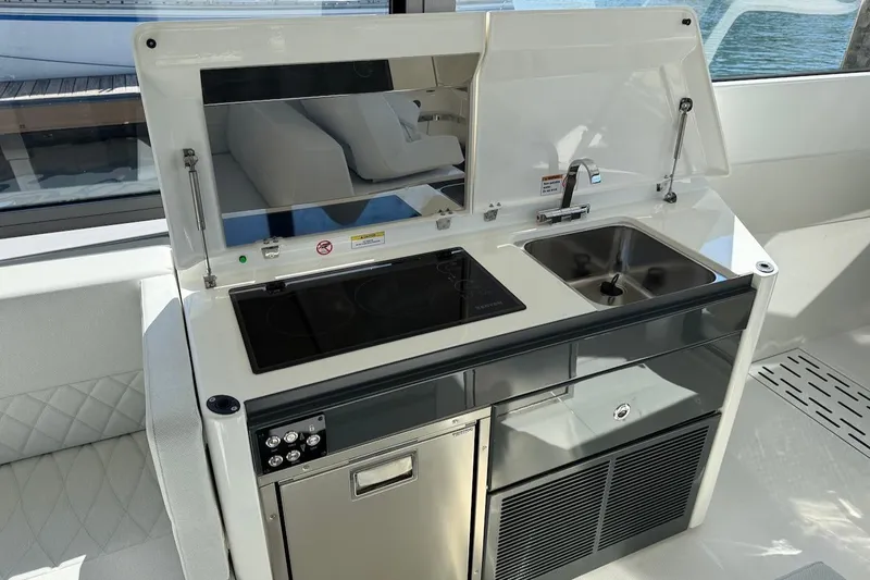 Slide: The Image of Modern kitchenette on Saxdor 400 GTC 2026 boat with stove, sink, and storage. - 25