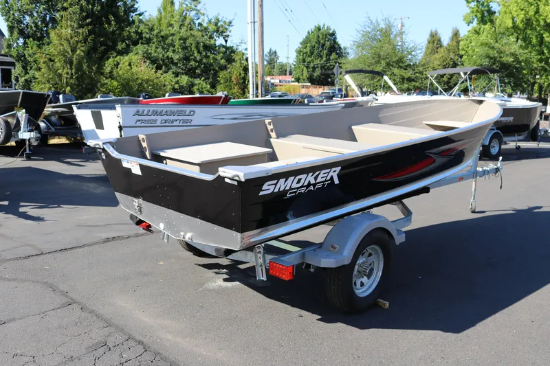 Slide: The Image of 2025 Smoker Craft Voyager 16 boat on trailer, parked outdoors. - 2